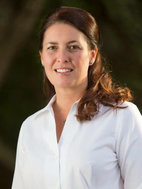 A woman in white shirt smiling for the camera.